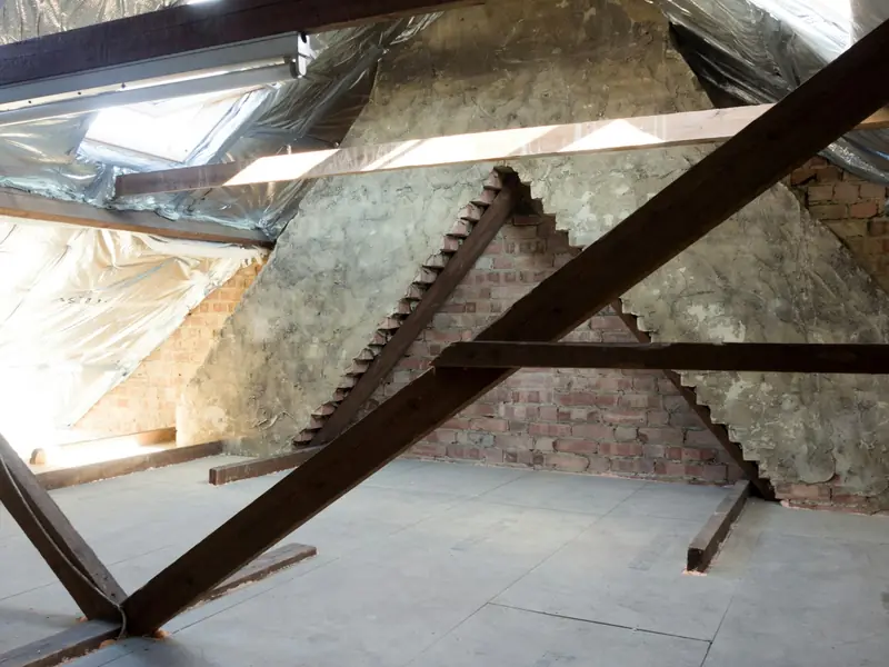 Attic framing with a brick chimney base, wood rafters and reflective insulation